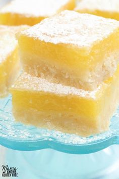 three pieces of lemon cake sitting on top of a blue glass plate with powdered sugar