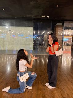 two women are sitting on the floor and one is covering her mouth