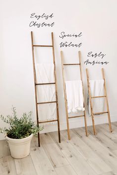 two wooden ladders with towels on them next to a potted plant and white wall