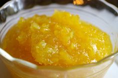 a glass bowl filled with oranges sitting on top of a white tablecloth next to a spoon