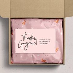 an open box with pink wrapping paper and thank you someone written on the side in black ink