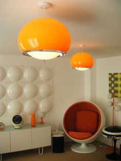 an orange chair sitting in front of a white wall with balls on it and lights hanging from the ceiling