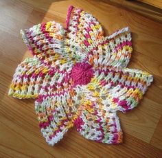 a multicolored crocheted flower sitting on top of a wooden floor next to a window