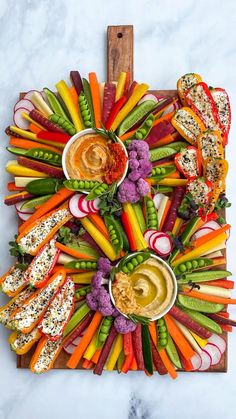 a platter with carrots, celery, radishes and hummus