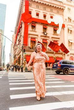 a woman in an orange dress crossing the street