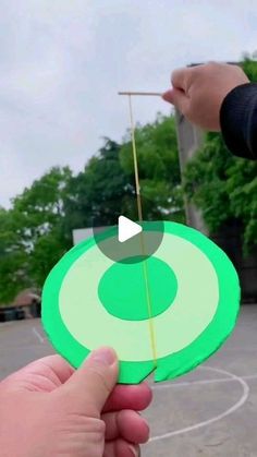 someone holding a green frisbee in their hand and pointing it at the target