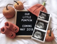 a sign that says our little pumpkin is coming may 2019 next to some baby booties