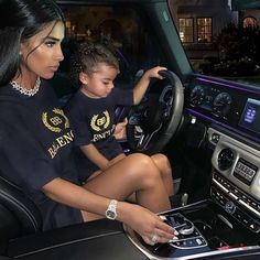 a woman and child sitting in the driver's seat of a car