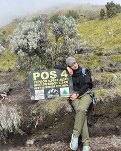 a man sitting on the side of a mountain next to a sign that says posa