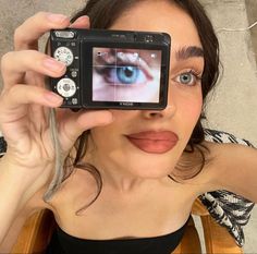 a woman is holding up a camera to take a selfie with her blue eye