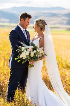 a bride and groom standing in the middle of a field