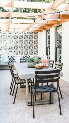 an outdoor dining table and chairs under a pergolated roof