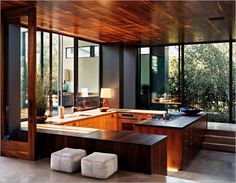 an open kitchen with wooden cabinets and counter tops in front of large glass windows that look out onto the backyard