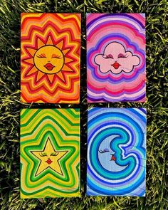 four colorful paintings on grass with one sun and the other moon