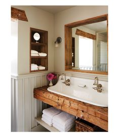 a bathroom sink sitting under a mirror next to a shelf with folded towels on it