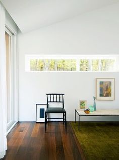 a living room with white walls and wood flooring on the wooden floor, along with two black chairs