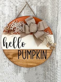 a wooden sign that says hello pumpkin hanging on the side of a door with a bow