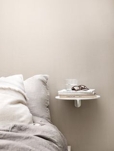 a bed with two books and a cup on top of the shelf next to it