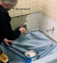 a man in black shirt painting a wall with blue paint