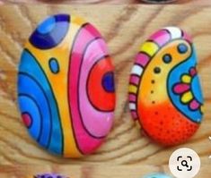 three colorful painted rocks sitting on top of a wooden table next to each other with the words, happy easter written below them