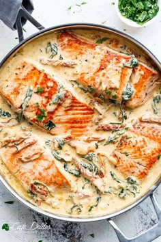 a pan filled with food on top of a white table next to silver spoons