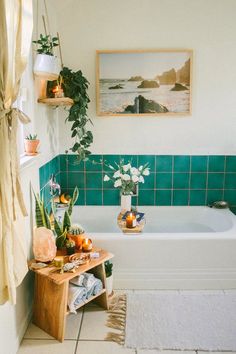 a bathroom with green tiles and plants in the bathtub, along with potted plants