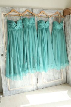 three bridesmaid dresses hanging on a door