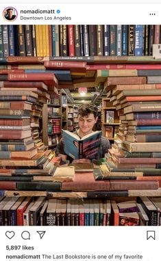 a man is reading a book in the middle of a room made out of books