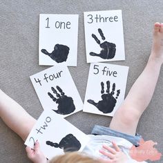 a child is laying on the floor with four handprints in front of them