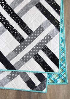 two black and white quilts sitting on top of a wooden floor next to each other