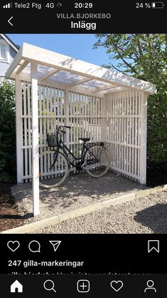 a bike is parked in front of a white pergolated area with gravel on the ground