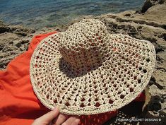 a person is sitting on the beach with a hat in their lap and looking out at the water