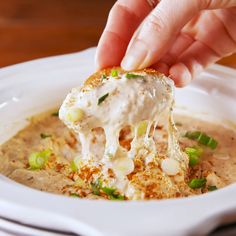 a person dipping some kind of food into a bowl