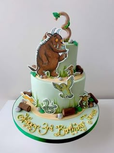 a three tiered birthday cake with an animal theme on the top and bottom layer