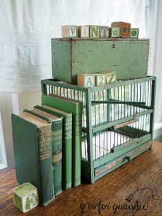 several books are stacked on top of each other in an old green box with letters