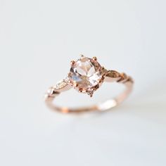 an engagement ring with two diamonds on the side and a pink morganite in the center