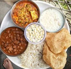 a white plate topped with lots of different types of food next to rice and bread