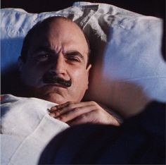 a man laying in bed with a moustache on his face