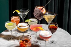 a table topped with glasses filled with different types of drinks and garnished with lemon wedges