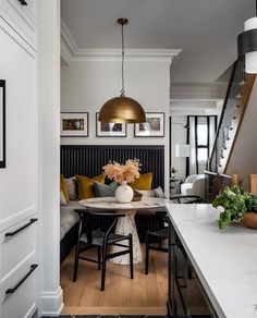 a kitchen with white counter tops and black chairs next to a dining room table that has flowers in a vase on it