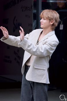 a young man standing on top of a sidewalk holding his hands out in front of him