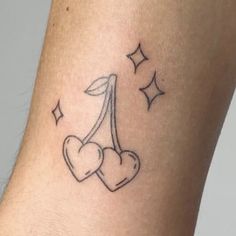 a small tattoo on the ankle of a woman with two hearts and stars around it