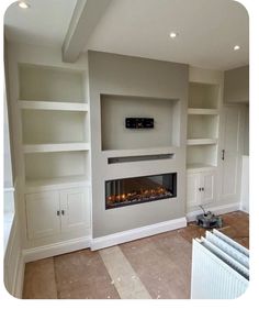 an empty living room with built - in shelves and a fire place on the wall