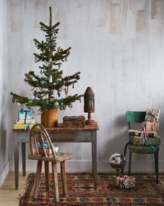 a small christmas tree sitting on top of a wooden table next to a chair and desk