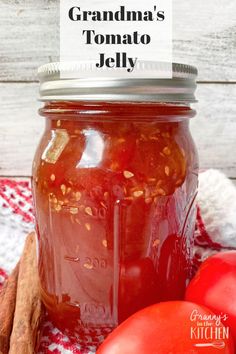 a jar filled with tomato sauce next to some tomatoes and cinnamon on a red checkered table cloth