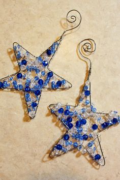 two blue and white glass stars hanging from metal wire on a beige background with swirls