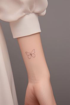 a woman's wrist with a small butterfly tattoo on the left side of her arm