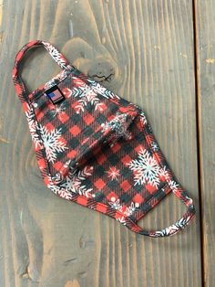 a red and black plaid bag sitting on top of a wooden floor next to an apple