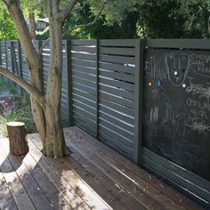 a wooden deck next to a tree and fence