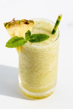 a pineapple and mint smoothie in a glass with a green straw garnish